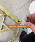 Hand holding adjustable aluminum furniture legs M10 1.5mm threaded metal feet near 10mm screw hole on gold frame