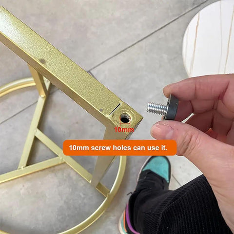 Hand holding adjustable aluminum furniture legs M10 1.5mm threaded metal feet near 10mm screw hole on gold frame
