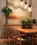 Industrial Three Light Pendant Light With Adjustable Height Up To 34 Inches, Black Finish And Clear Glass Shade in dining room setting