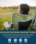 Woman sitting in Comfort Pro Rocker Folding Outdoor Chair For Camping And Backyard Hangouts, enjoying a scenic view.