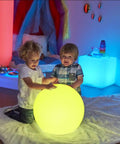 Two children playing with Cordless 16 Inch LED Glowing Ball Light With Remote RGB Color Changing Waterproof Glow Ball indoors