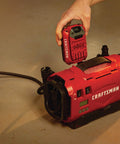 V20 Tire Inflator Portable Air Compressor With Cordless 120V Corded And 12V Car Adapter Modes beside a car tire inside a garage.