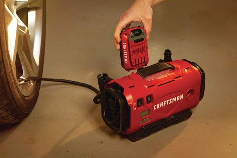 V20 Tire Inflator Portable Air Compressor With Cordless 120V Corded And 12V Car Adapter Modes beside a car tire inside a garage.