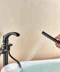 Dual Function Freestanding Tub Filler Faucet In Oil Rubbed Bronze With Waterfall Flow, hand shower in use over tub