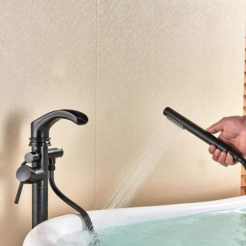 Dual Function Freestanding Tub Filler Faucet In Oil Rubbed Bronze With Waterfall Flow, hand shower in use over tub