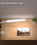 Ultra Versatile LED Desk Lamp With Clamp illuminating wide desk area with book and plant, showcasing flexible gooseneck and large illumination area.