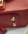 Close-up of Straight Up Solid Brass Purse Feet With Flat Head Studs on a red leather handbag, emphasizing shiny finish and sturdy design.