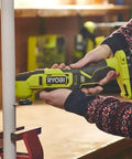 Person using Built Different 18V Cordless Multi Tool to cut a white pipe in a workshop, showcasing its versatility and precision.