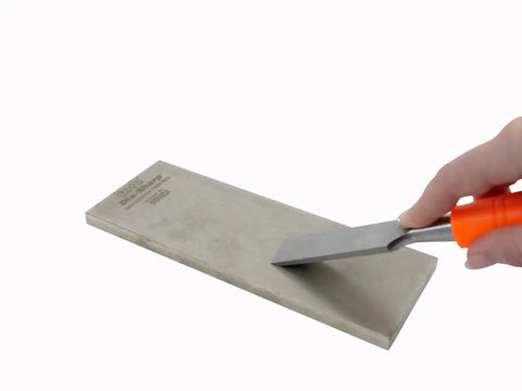 Hand using chisel on Dia Sharp Diamond Knife Sharpener For Home Chefs Extra Extra Fine Diamond Sharpening Stone Eight Inch Beige.