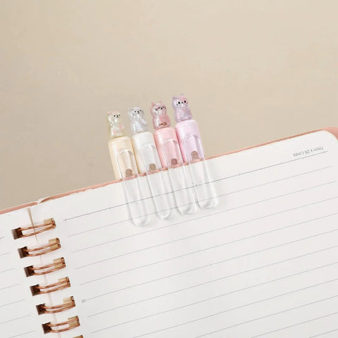 Four Cute Retractable Gel Pens With Glitter Cat Design, 0.5mm Fine Point Black Ink, in pink, yellow, pink, and purple on notebook