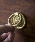 Hand grasping Brass Cabinet Ring Knobs Set, Gold Round European Style Drawer Pulls on wood surface