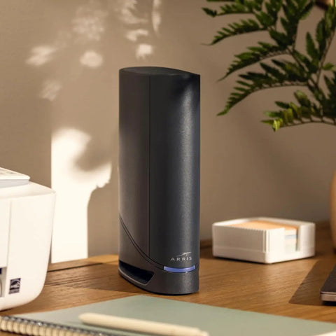 Black G34 Cable Modem Router Combo With DOCSIS 3.1 And WiFi 6 AX3000 on a desk next to office items