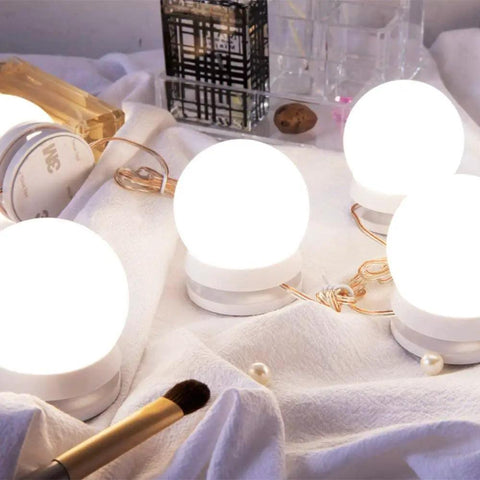 Hollywood Style LED Vanity Lights Kit With 14 Dimmable Bulbs And AC Adapter Stick On Makeup Lights For Dressing Room No Fuss Soft 4000K Daylight Without Eye Strain Mirror Not Included, showcasing glowing bulbs on a vanity table with makeup accessories suggesting elegant setup.