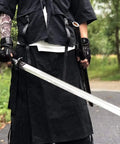 Man holding hand forged Longquan style dao sword with high carbon steel blade full tang and dope matte black wooden scabbard