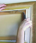 Hands installing Steel Wire Rope Picture Hanging Wire 25 Ft Corrosion Resistant Galvanized Cable on a frame for gallery display