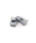 Two gray APMT1604PDER-M2 carbide inserts with central holes for CNC milling tools
