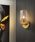 Super Sleek Modern Copper Brass Wall Sconce With Geometric Cylindrical Glass Shade For Bedroom Bedside And Living Room E14 Compatible Accent Lamp, mounted on dark wall beside art.