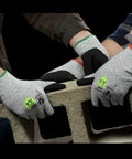 Two pairs of Griffin Gear ANSI A4 Liquid Repellent Nitrile Work Gloves lifting a concrete block, showing grip and protection.