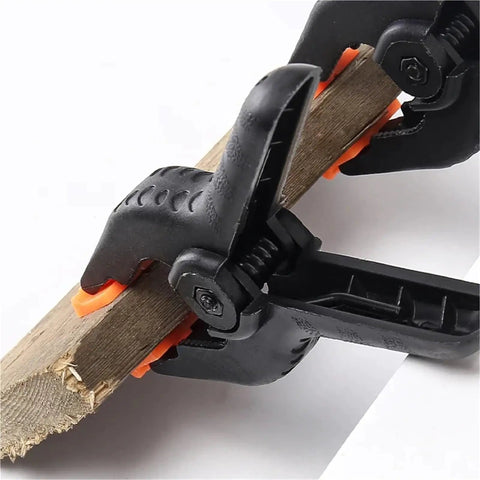 Close-up of a four inch durable plastic nylon spring clamp holding a wooden piece, Must Have Four Inch Spring Clamps Set For Woodworking And Photo Studio Backdrops Durable Plastic Nylon Clips For Furniture Accessories Space Saving Desk Organizer To Keep Papers Notes And Gear Neat.