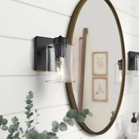 Set Of Two Matte Black Wall Sconces With Clear Glass Shade, Industrial Farmhouse Vanity Lighting Fixtures beside a round mirror.