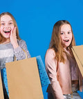 Two girls holding Bulk 500 Pack Heavy Duty Kraft Paper Bags 10x13 Inches With Handles, looking surprised.
