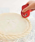 Pastry wheel dough cutter with red handle used to crimp pie crust edge, front view.