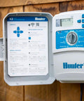 14-Station Outdoor Sprinkler Controller with Wi-Fi Smart Irrigation System Hydrawise Compatible Weather Based Scheduling for Lawn and Garden, Remote Management from Smartphone or Desktop shown installed on wooden wall