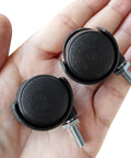 Hand holding two 1.2 Inch Nylon Wheel Caster With M6 Threaded Stem Non Brake Swivel, showing black wheels and silver stems.