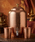 Pure Copper Water Dispenser Pot Hand Hammered 4 Liter with two copper glasses on a wooden table