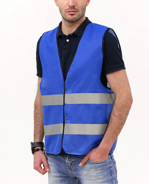 Man wearing blue safety vest with reflective tape, hands in pockets. Not related to 10 Pack Hi Visibility Safety Vests For Adults With Reflective Tape Bright Orange Color Breathable Lightweight Construction Workwear For Men And Women.