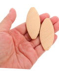 Hand holding two 100 PC Wood Biscuits For Woodworking Pro Grade Slotting And Plywood Joinery Tool Easy Fit For Furniture Assembly Durable Hardwood