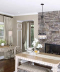 Dining area with Topsail Three Light Inverted Pendant In Polished Chrome above a table, stone wall backdrop, modern decor