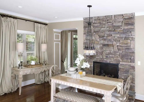 Dining area with Topsail Three Light Inverted Pendant In Polished Chrome above a table, stone wall backdrop, modern decor