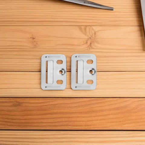 Two stainless steel snap lock mounting clips on wooden surface, part of 100 Piece Stainless Steel Wall Panel Buckles Hardcore Snap Lock Mounting Clips Zero Hassle Quick Setup For Drywall Furring Strips Baseboards Furniture Fixes Rock Solid Hold For Home Office Spaces.