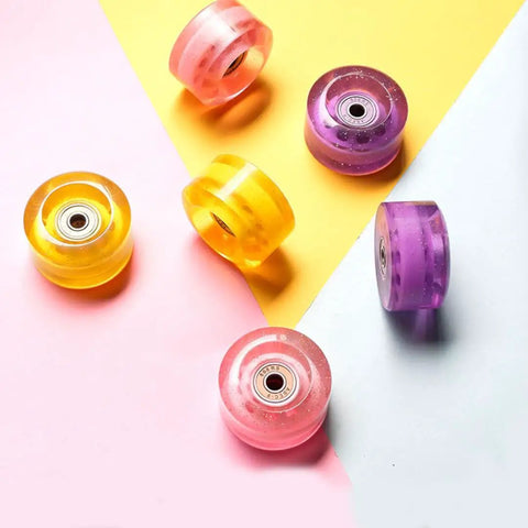 Colorful assortment of eight 58x32mm quad skate wheels 82A with bearings, pink sesh for indoor double row skates, shown on pastel background.