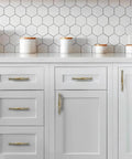Kitchen cabinet with Two Pack 4 Inch Hole-Center Antique English Brass Drawer Pulls, handles on white drawers, hexagonal tile backsplash.