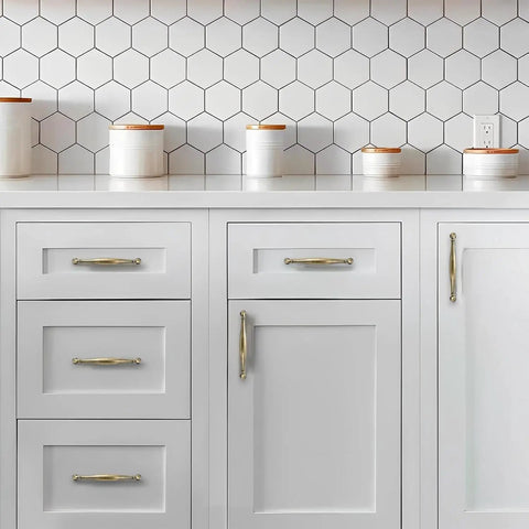 Kitchen cabinet with Two Pack 4 Inch Hole-Center Antique English Brass Drawer Pulls, handles on white drawers, hexagonal tile backsplash.
