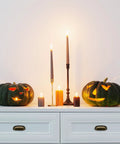 Carved pumpkins and candles on white dresser with black handles