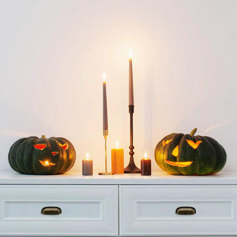 Carved pumpkins and candles on white dresser with black handles