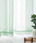 Close-up of Christmas Green Semi Sheer Curtains with linen look, light filtering, featuring durable fabric, in a cozy home setting.