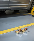 Welding Ground Clamp Assist Holder Two Pack with flexible copper alloy base, shown on garage floor near vehicle