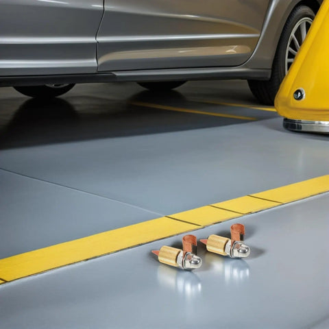 Welding Ground Clamp Assist Holder Two Pack with flexible copper alloy base, shown on garage floor near vehicle