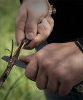 Person using 13 In 1 Stainless Steel EDC Multitool With Nylon Sheath For Camping, Hiking, And Fishing to cut a branch with knife blade