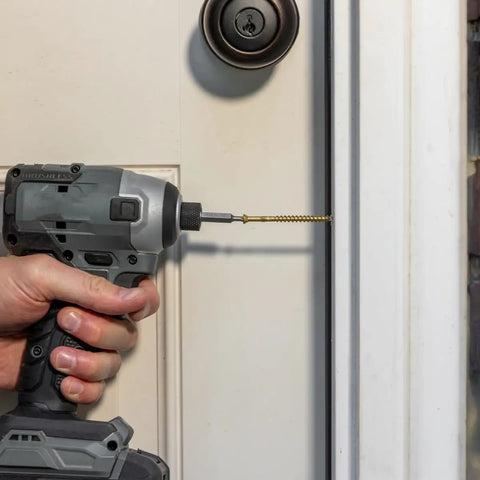 Using a drill with a Top Shelf Exterior Trim Screw Nine By Three Inch Bronze Self Drilling Wood Fastener on a door frame.