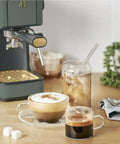 Rock Solid Compact Espresso Machine In Fresh Thyme Green with espresso and latte drinks on a wooden table.