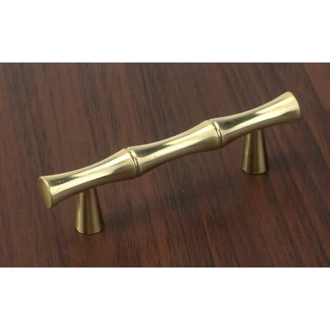 Set Of Four Bamboo Shape Cabinet Pulls In Brushed Gold Finish With Center Hole 2.5 Inches Including Screws 3.7 Inch Total Length Durable Zinc Alloy Drawer Pulls For Kitchen And Furniture, shown installed on wood surface