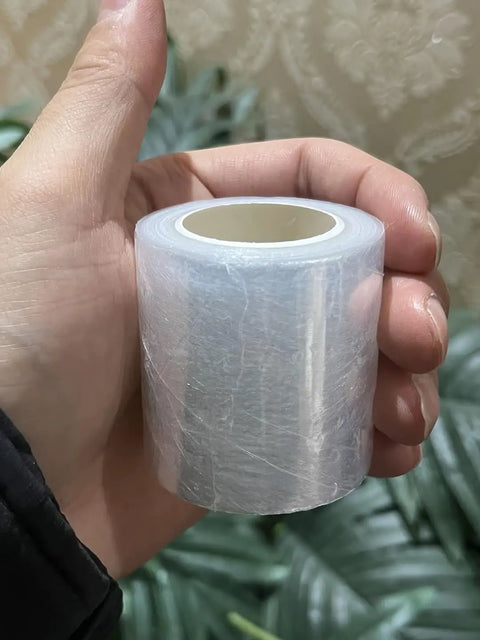 Hand holding a compact Stretchable Shrink Film Roll for Bottled Packaging and Non-Heated Bottle Sealing Machine, portable design.