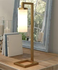 Tall Floor Lamp With Glass Milk Shade In Brass Finish, Stands At 67.75 Inches Tall, Steel Base, on wooden desk with books and candles