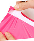 Pink Thickened Waterproof Packaging Bags 17x30cm 100 Pack Tear Resistant Self Seal Poly Mailers being handled