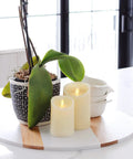 Ivory Scalloped Edge Flameless LED Pillar Candle With Real Wax Look Moving Flame No Mess, next to green plant